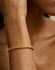 Close-up of a person's arm with a gold bracelet, skin texture visible