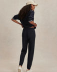 Person wearing a navy tracksuit and white cap on a plain background