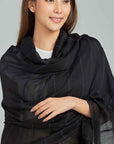 Woman wearing a black scarf on a gray background