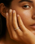 Close-up of a woman's face with one hand gently touching her cheek, on a neutral background