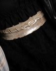 Person wearing a black outfit with a metallic belt
