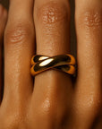 Gold ring on a person's finger with a warm brown background