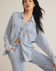 Woman wearing a light blue denim outfit against a neutral background