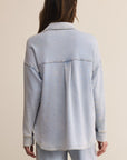 Light blue denim jacket worn by a person on a beige background