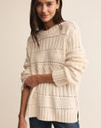 Woman wearing a cream knitted sweater against a beige background