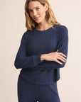 Woman wearing a navy ribbed sweater and pants on a beige background