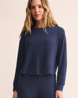 Woman wearing a navy ribbed sweater and pants on a beige background