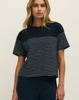 Woman wearing a navy blue and white striped shirt against a plain background