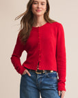 Woman wearing a red cardigan and blue jeans on a beige background