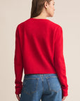 Person wearing a red sweater and blue jeans on a beige background