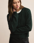 Woman wearing a dark green sweater against a beige background