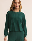Woman wearing a green ribbed sweater and pants on a beige background