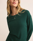 Woman wearing a green ribbed sweater against a plain background