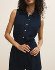 Woman wearing a navy sleeveless dress against a beige background