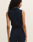 Woman wearing a navy blue sleeveless romper against a beige background