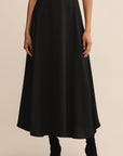 Black skirt worn by a person on a beige background