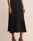 Black skirt worn by a person on a beige background