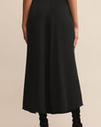 Black skirt worn by a person on a beige background