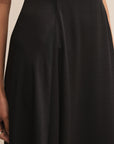 Black skirt worn by a person on a beige background