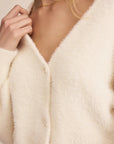 Close-up of a person wearing a cream-colored cardigan with a blurred background