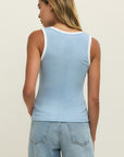 Woman wearing a light blue tank top and jeans on a plain background