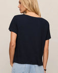 Woman wearing a black t-shirt and light blue jeans on a beige background