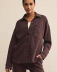 Woman wearing a brown shirt and pants against a beige background