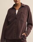 Woman wearing a brown button-up shirt with a neutral background