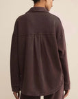 Person wearing a brown jacket and pants on a beige background