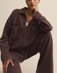 Person wearing a dark brown outfit with a plain background