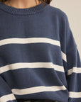 Navy sweater with white stripes worn by a person, on a neutral background