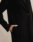Black coat with a button on a neutral background