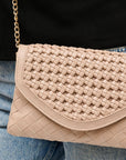 Beige woven handbag worn over the shoulder with a person wearing a black top and blue jeans.