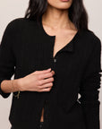 Woman wearing a black cardigan against a neutral background