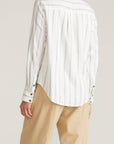 Person wearing a white striped shirt and beige pants on a plain background