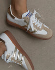 White and beige sneakers with brown soles on a neutral background