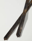 Two ends of a bronze leather belt on a white background
