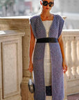 Woman wearing a long, patterned dress with a belt in an outdoor setting.