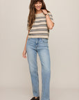 Woman wearing a striped shirt and blue jeans on a plain background