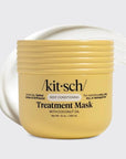 A yellow jar of kit'sch Treatment Mask with coconut oil, shown on a light gray background with a white cream smear behind it.