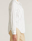 Person wearing a white striped shirt and beige pants on a plain background
