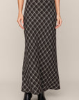 Person wearing a long plaid skirt on a plain background