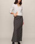 Woman wearing a white cardigan over a black and white checkered dress on a beige background