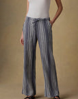 Person wearing blue and white striped pants with a white top on a beige background