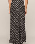 Person wearing a long plaid skirt on a neutral background