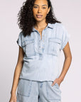 Woman wearing a light blue denim outfit with a matching top and shorts on a plain background