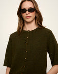 Woman wearing a dark green button-up shirt with a plain background