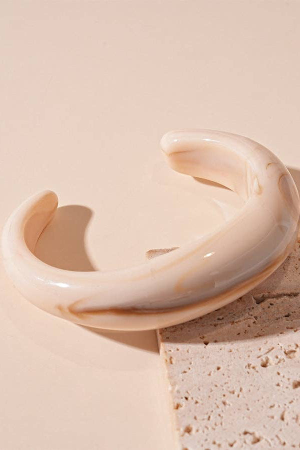 Beige ceramic bracelet on a textured beige surface