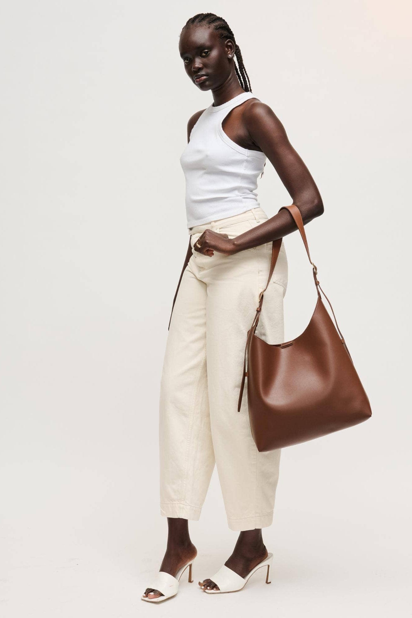 Woman holding a brown leather handbag against a white background