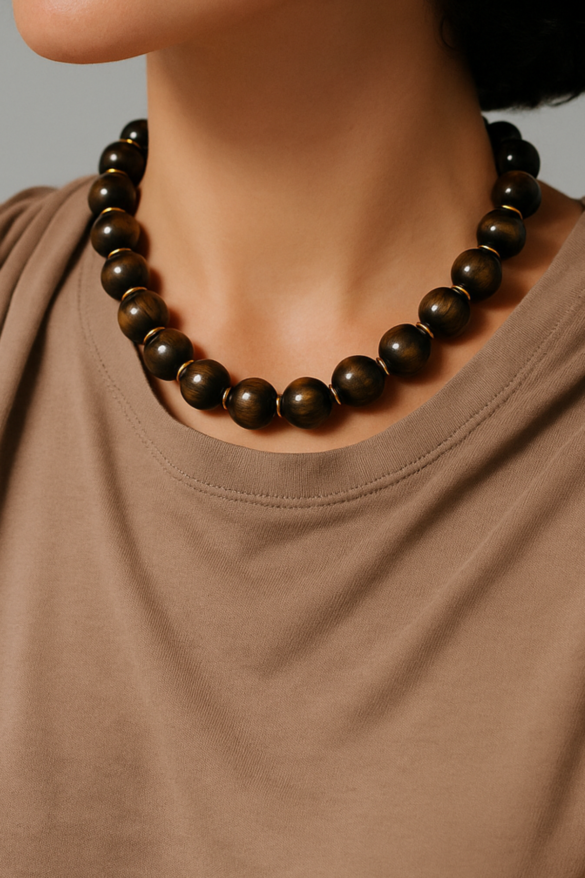 Person wearing a brown beaded necklace against a neutral background